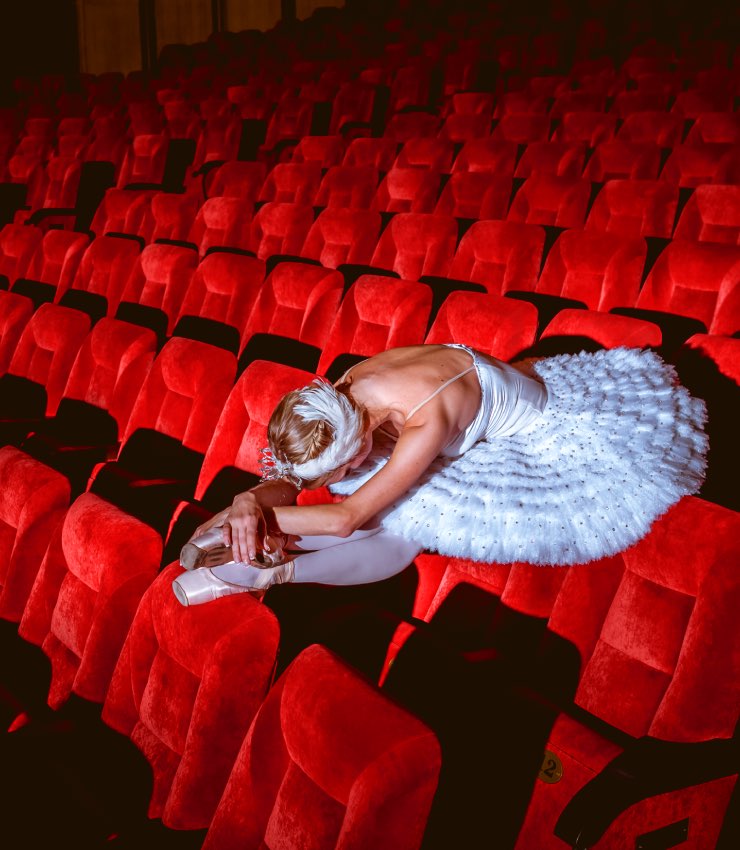 Bailarina con tutú descansando entre las butacas del teatro durante el concurso de danza y ballet