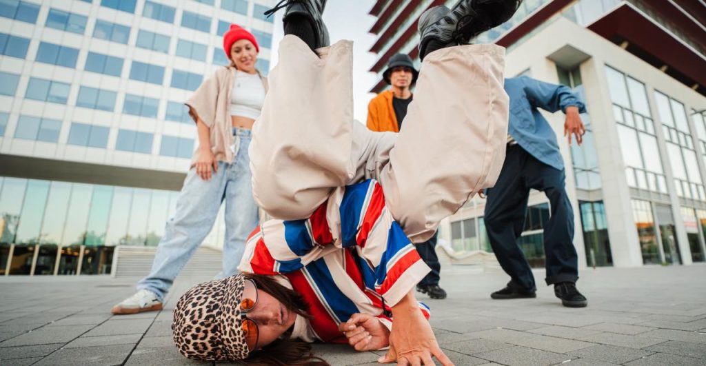 Dos bailarines de Breaking haciendo acrobacias en una batalla callejera.