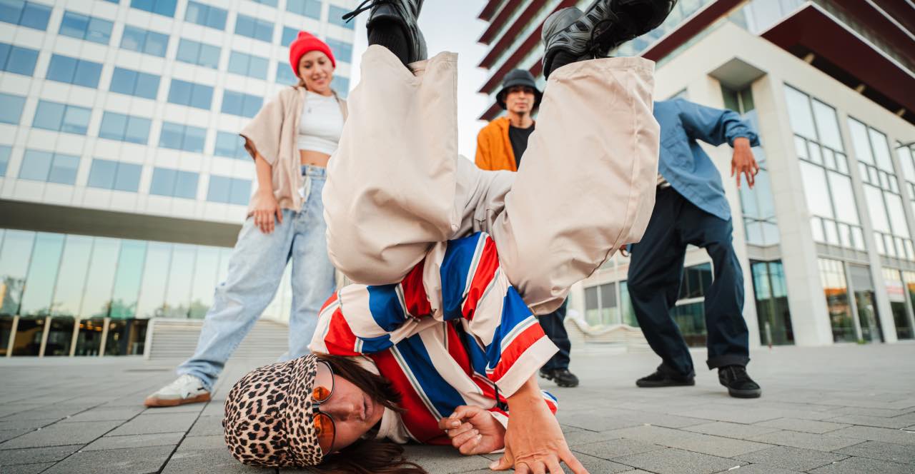 Dos bailarines de Breaking haciendo acrobacias en una batalla callejera.