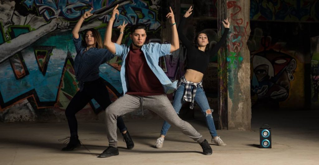 Una chica y dos chicos bailando Krumping con fuerza en la azotea de un edificio.