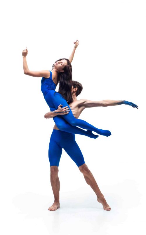 Jóvenes bailarines ejecutando movimientos elegantes de ballet clásico durante una competencia internacional en un escenario iluminado
